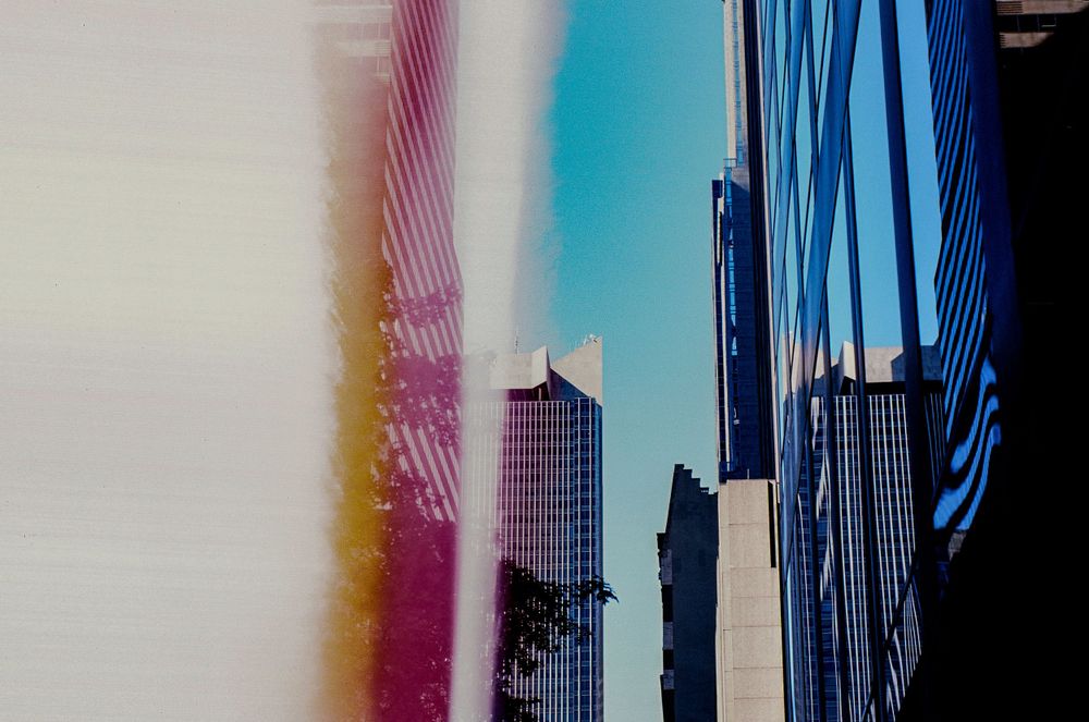 Modern skyscrapers photographed with colorful light leaks creating an artistic urban composition.