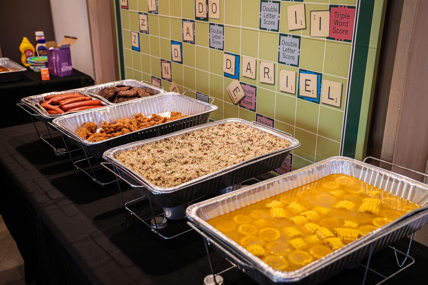 Large aluminum trays of catered food displayed on a buffet table.