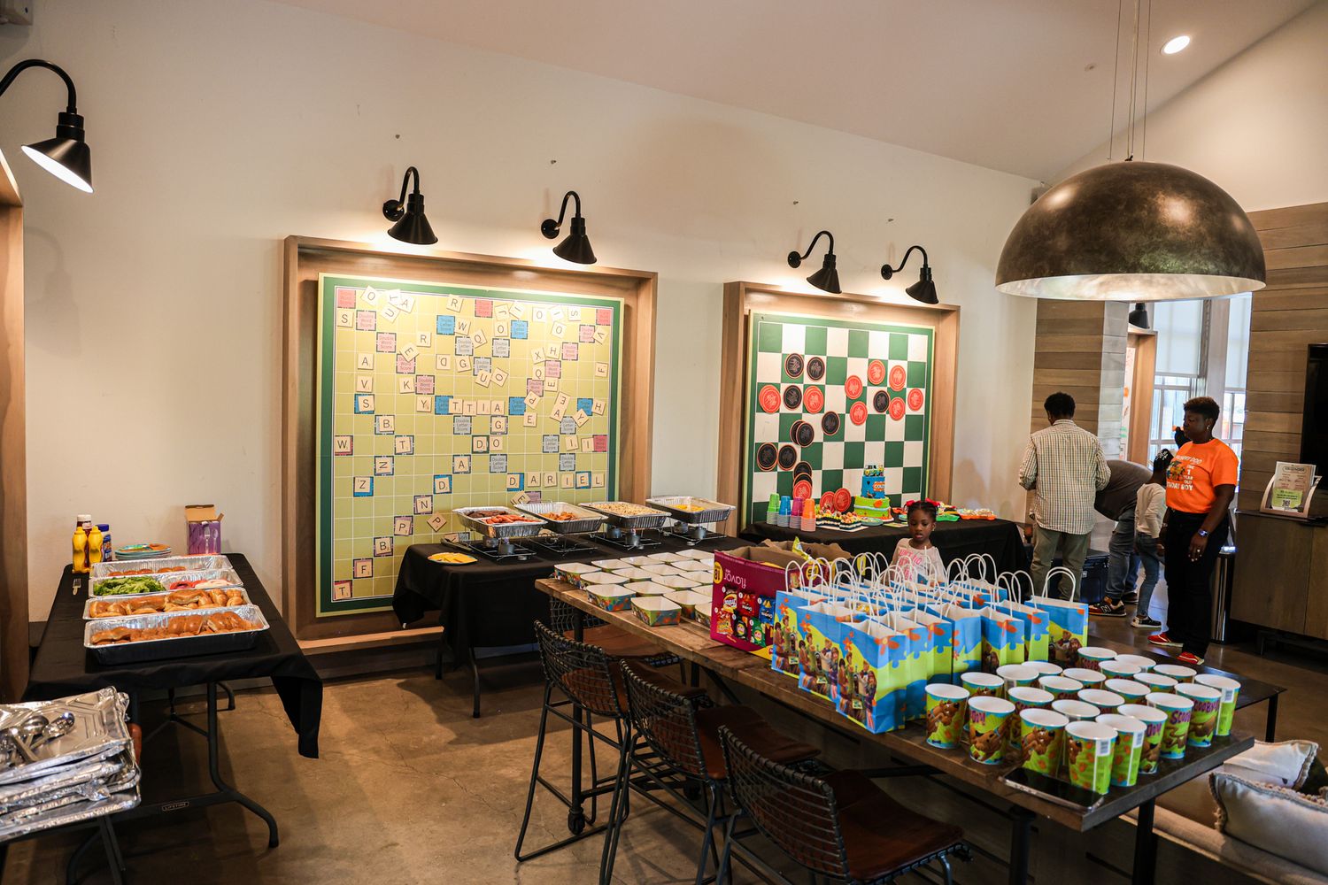 Party setup with tables displaying snacks and refreshments against beige walls.