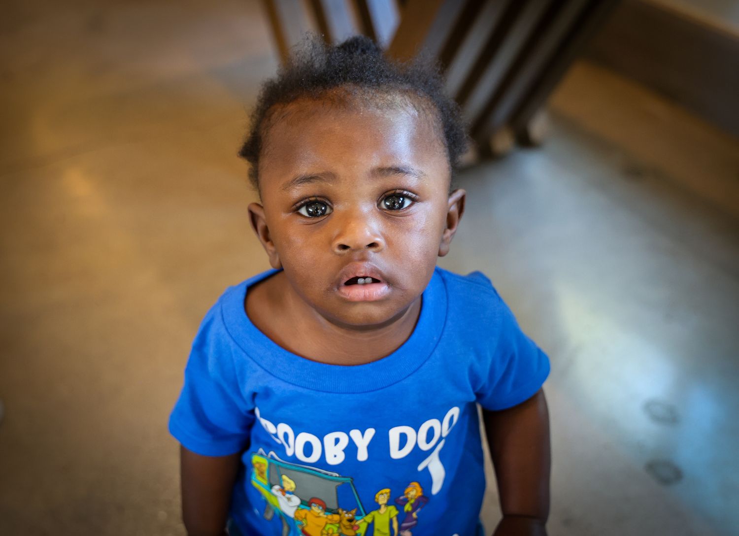 Child wearing a bright blue t-shirt with cartoon character design.