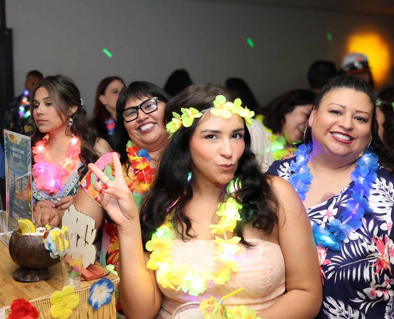 Party guests wearing colorful leis and tropical attire at a festive celebration.
