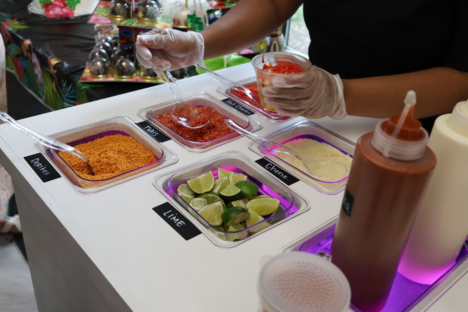 Buffet setup with various food trays and serving stations under purple lighting.