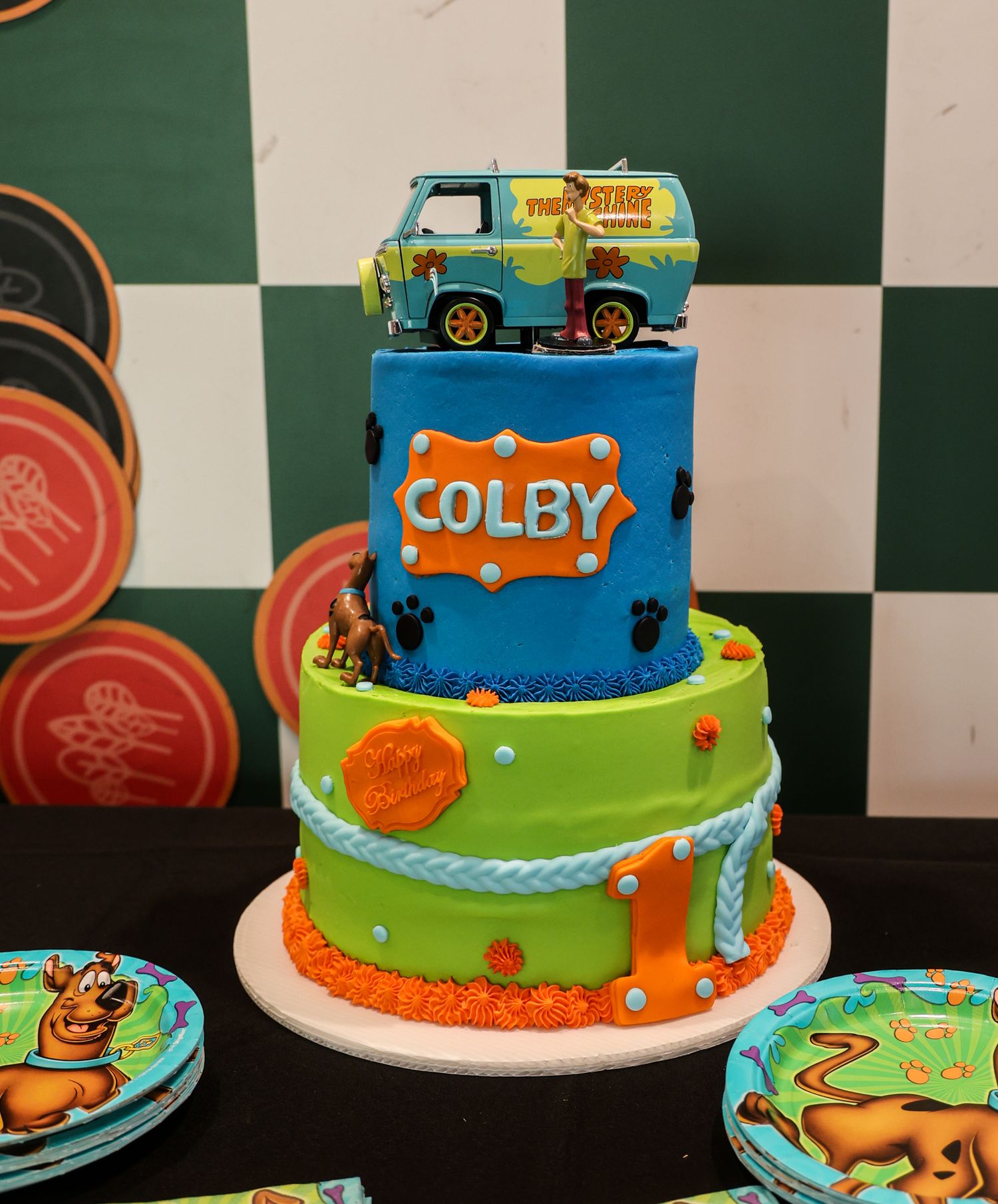 Colorful tiered birthday cake decorated with toy vehicles and the name Colby on top.