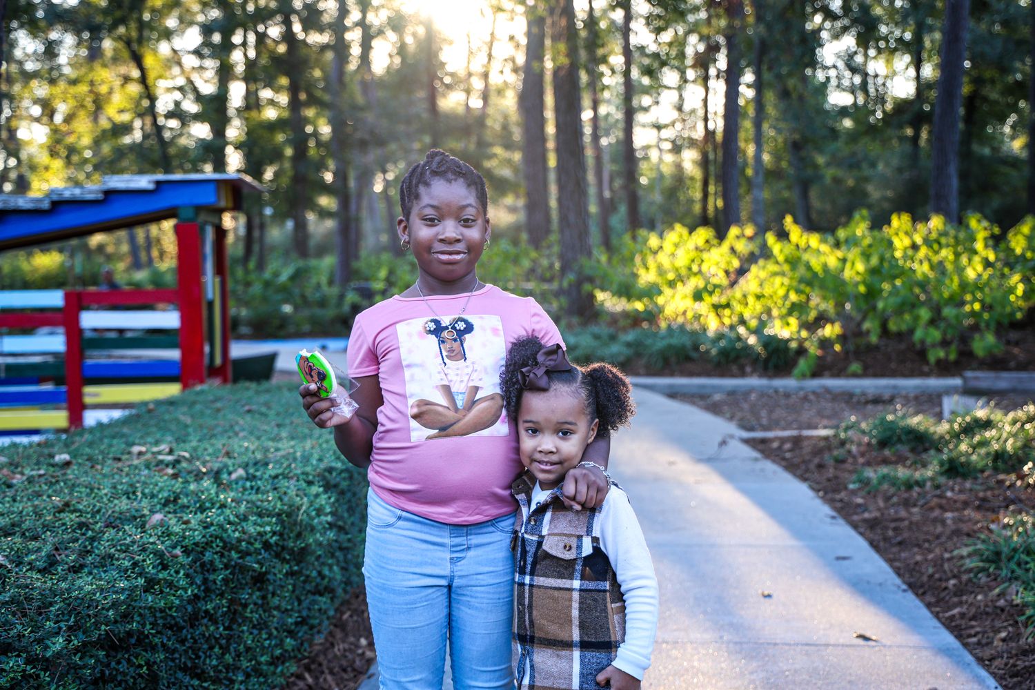 Playground and walking path surrounded by pine trees in late afternoon sunlight.