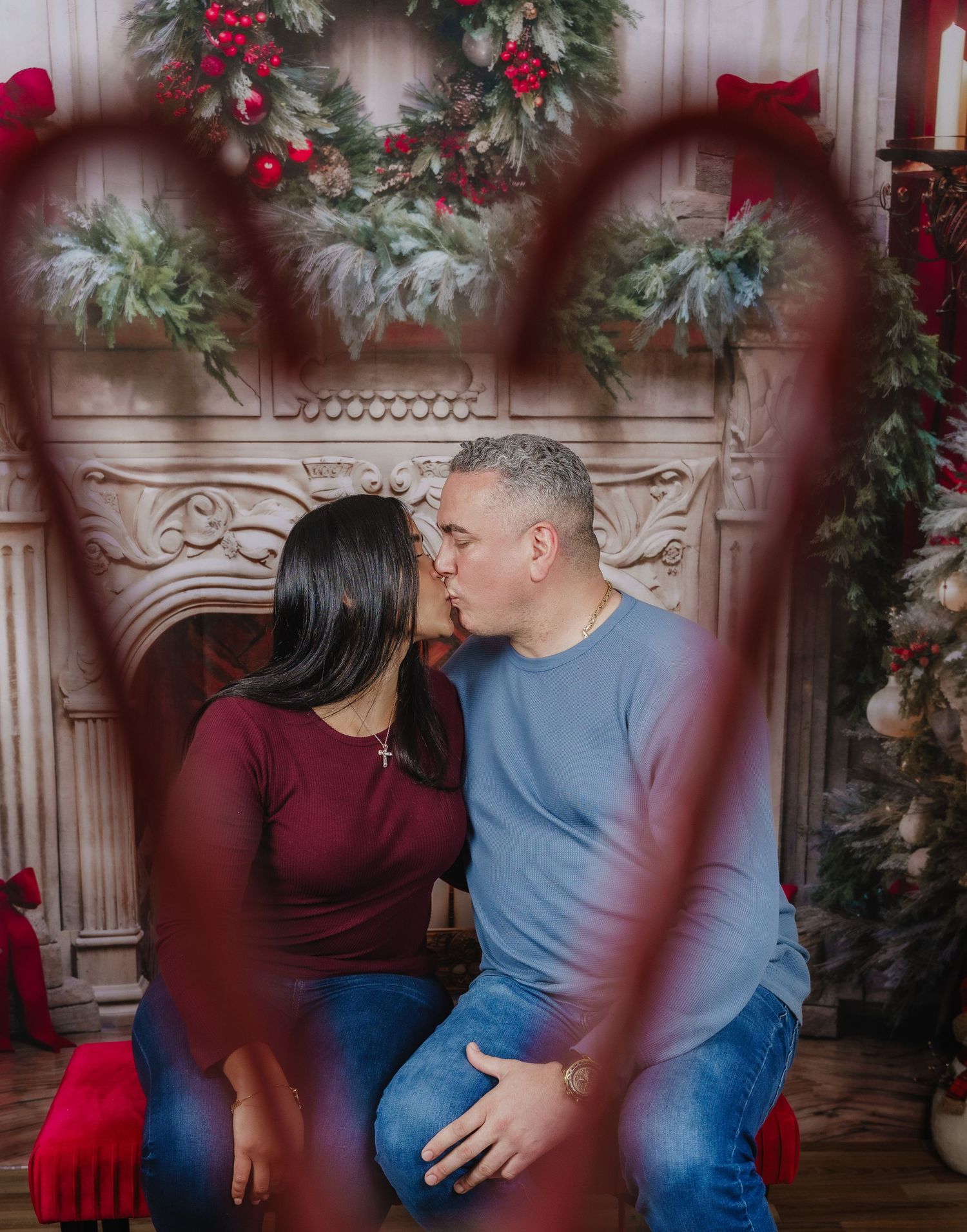 Romantic holiday photo through heart shape with decorated fireplace and Christmas wreaths.