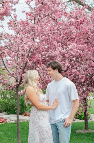 couple posing in front of pink flowering tree