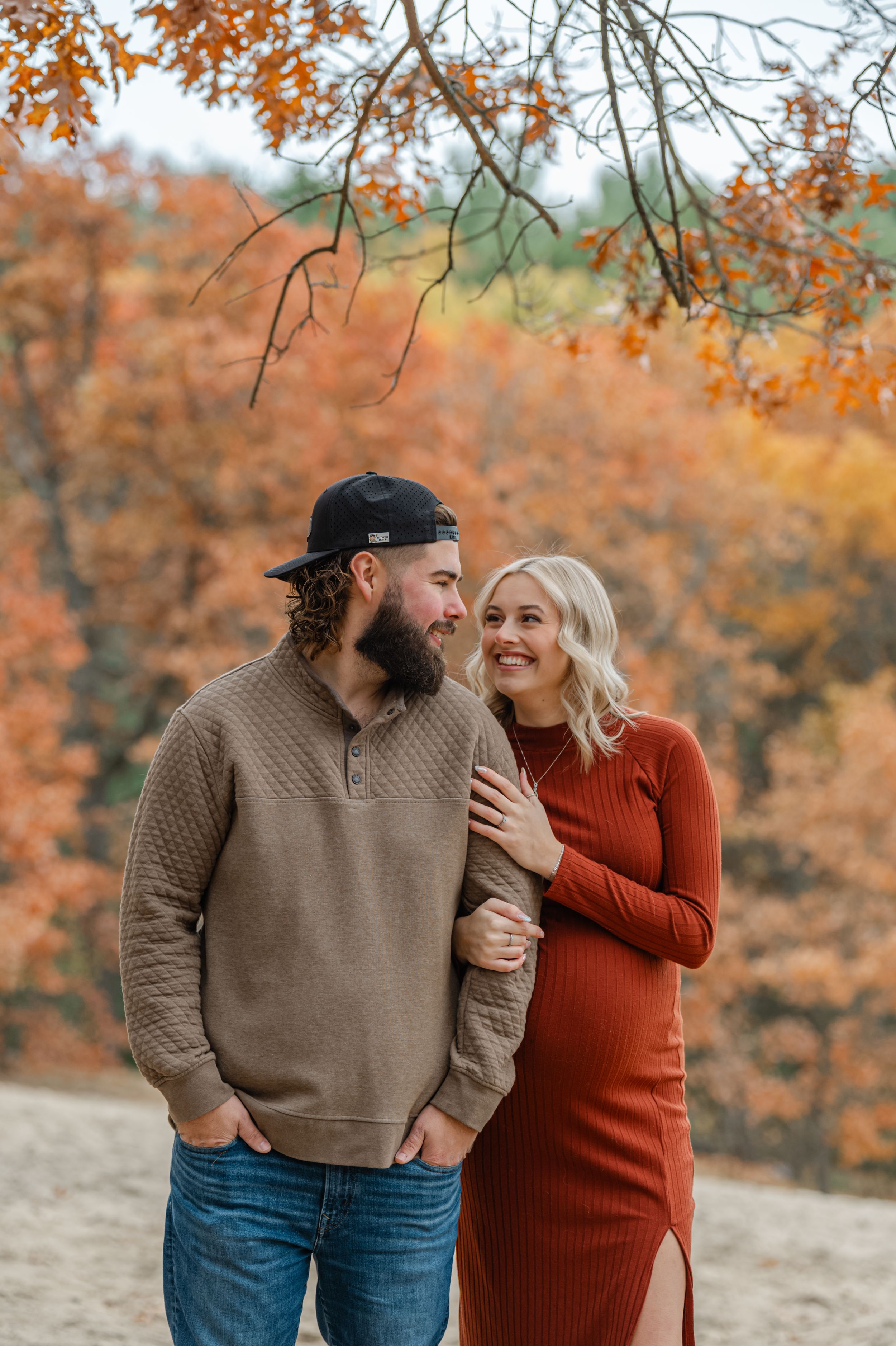 maternity photo of husband and wife smiling at eachother