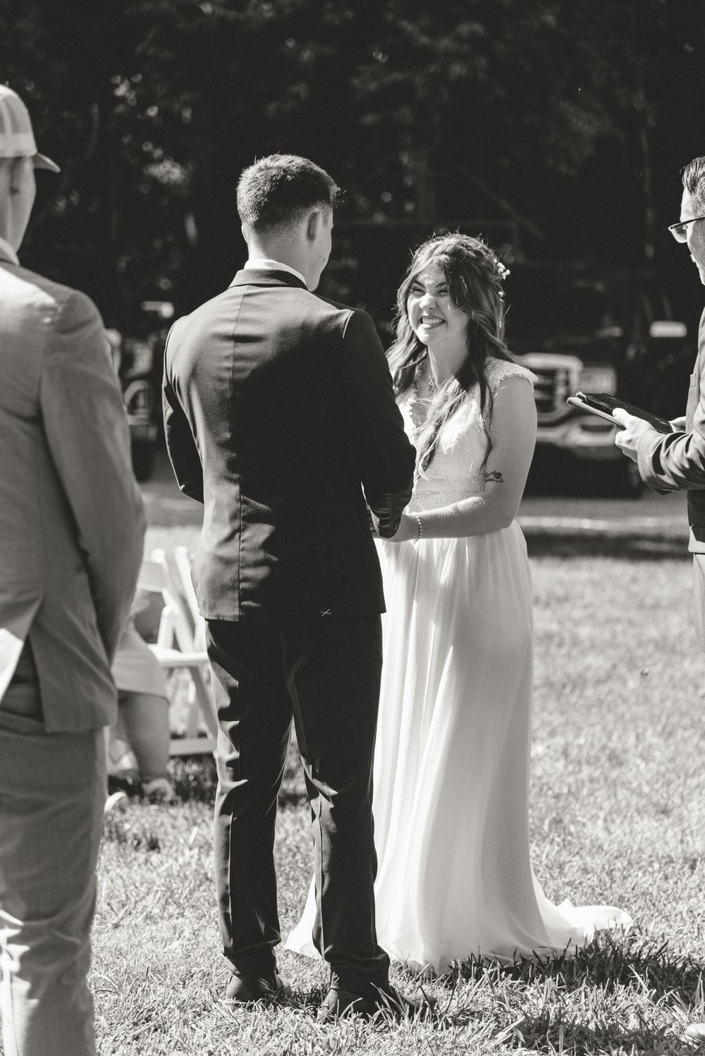 Black and white photo of wedding party members standing in a line on grassy lawn.