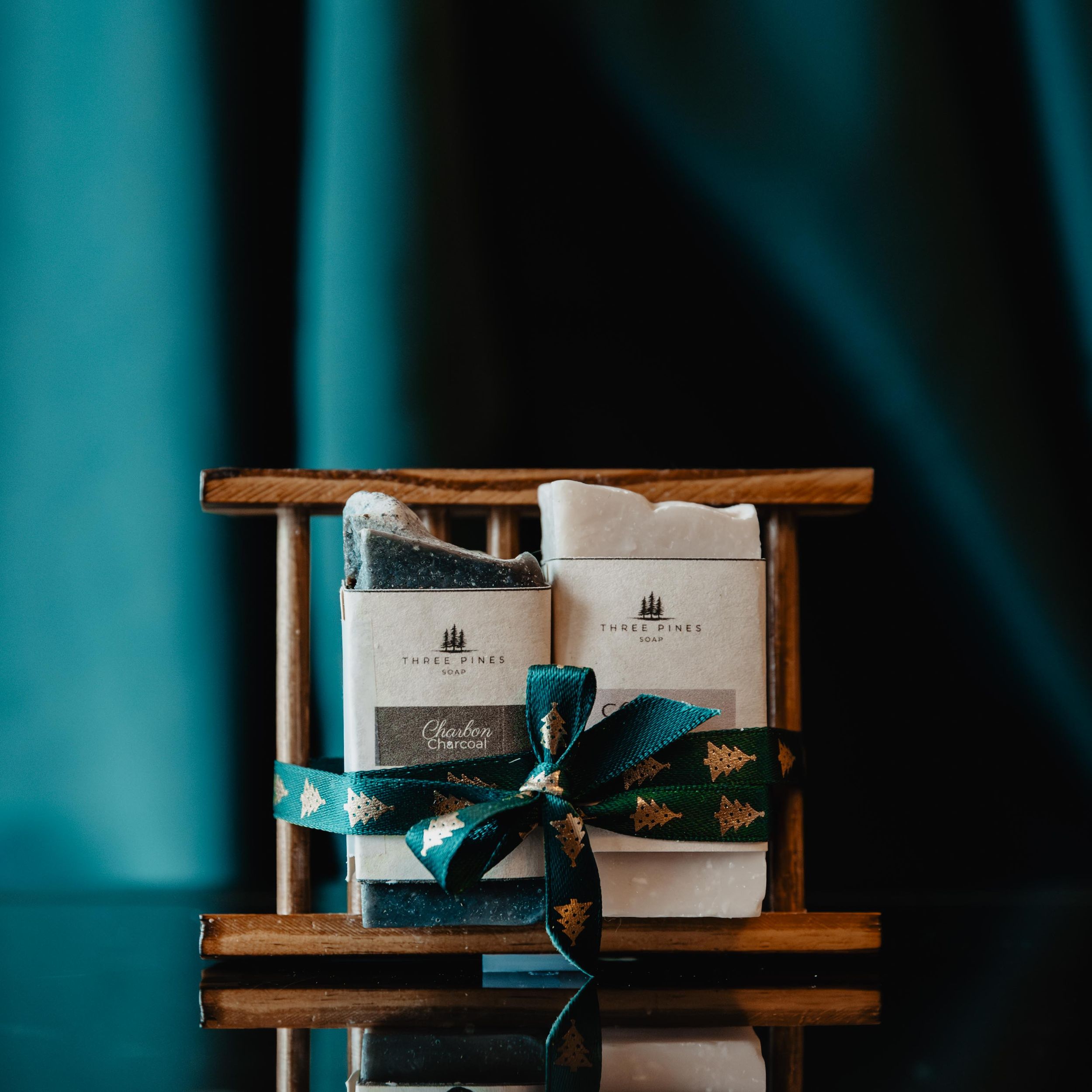 Luxury soap products arranged on wooden shelves with elegant teal ribbon packaging.