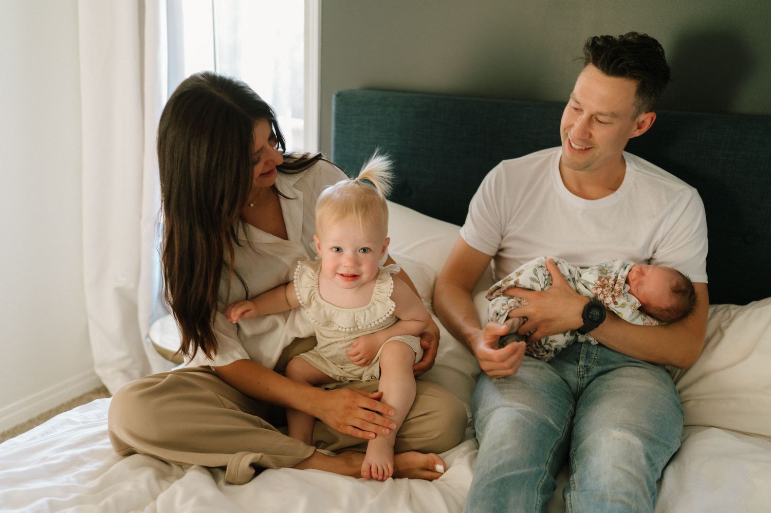 Family of four spending quality time together on bed.