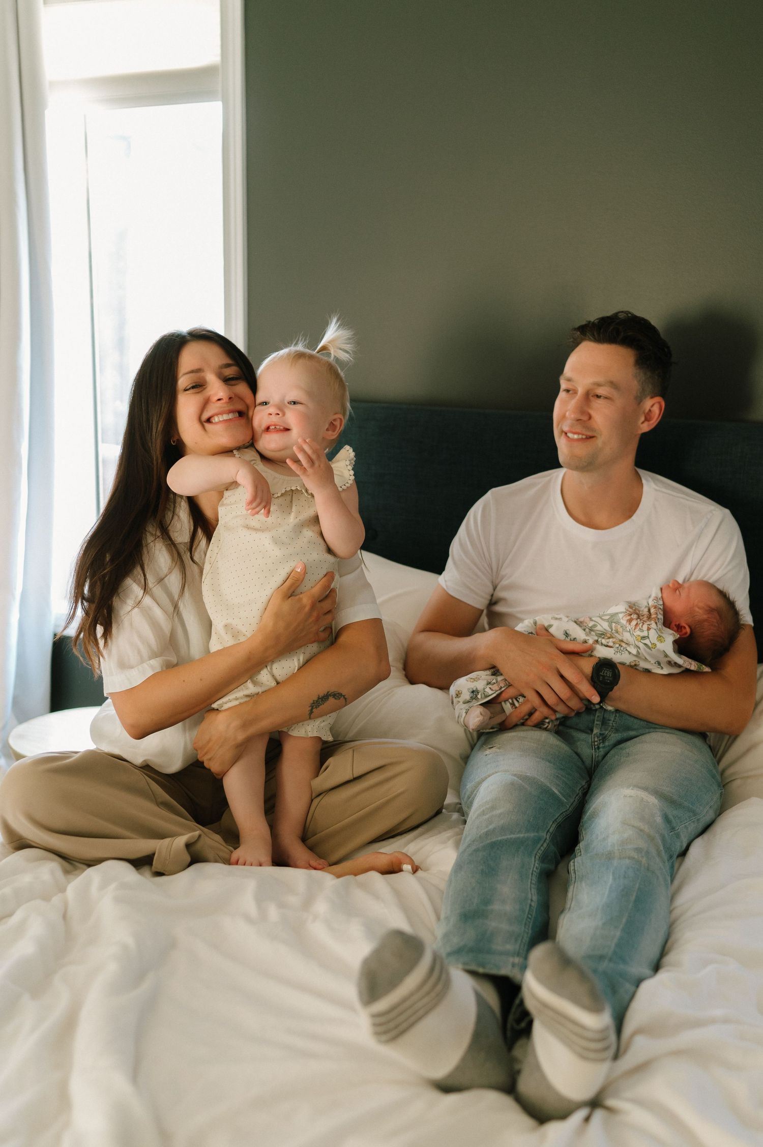 A happy family spends quality time together on a cozy bed in warm natural lighting.