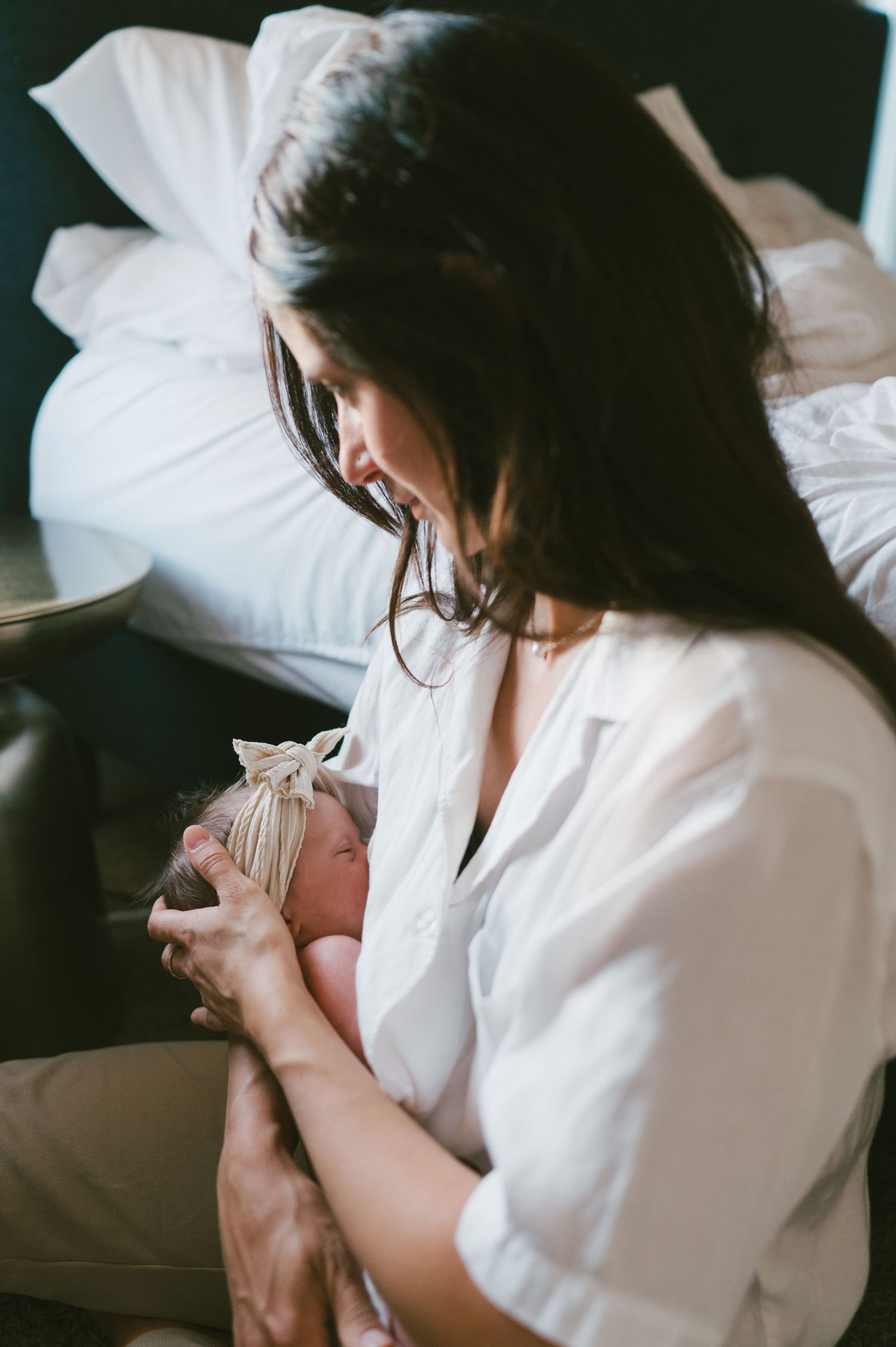 A tender moment between a parent and newborn in moody lighting.