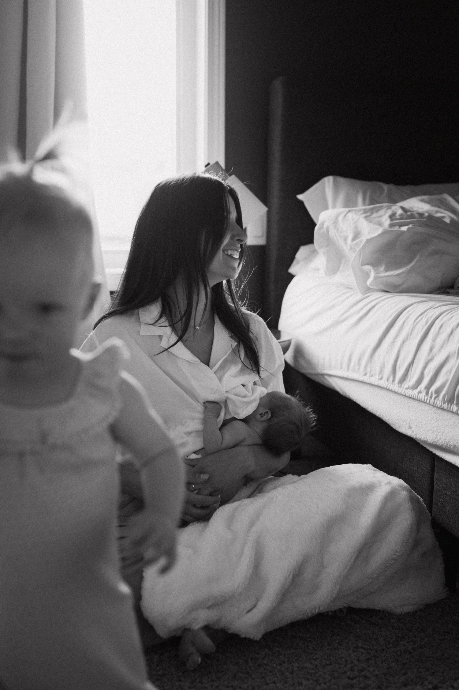 A black and white capture of a family's quiet moment together in a sun-lit room.