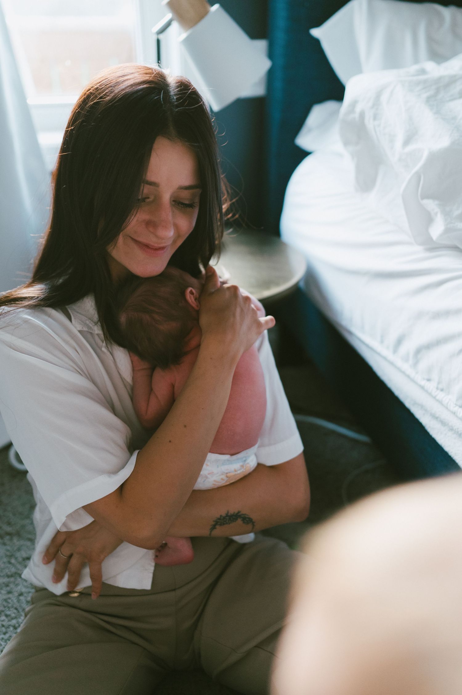 A parent in a white shirt holds their baby close in an emotional embrace.