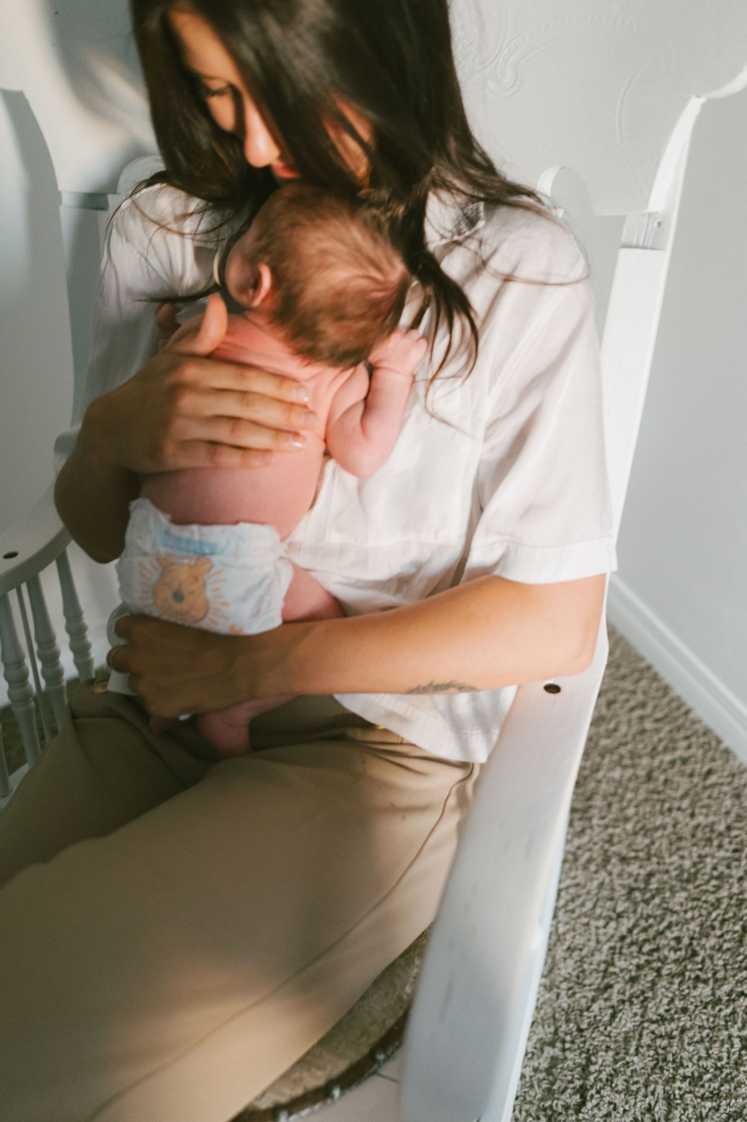 An intimate moment between parent and baby captured in soft window light.