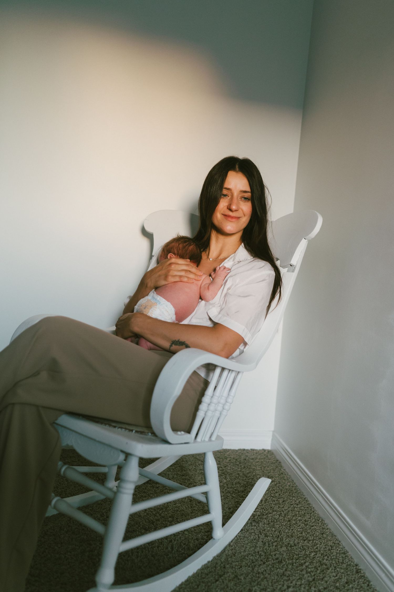 A peaceful moment in a white rocking chair as a parent cradles their baby.
