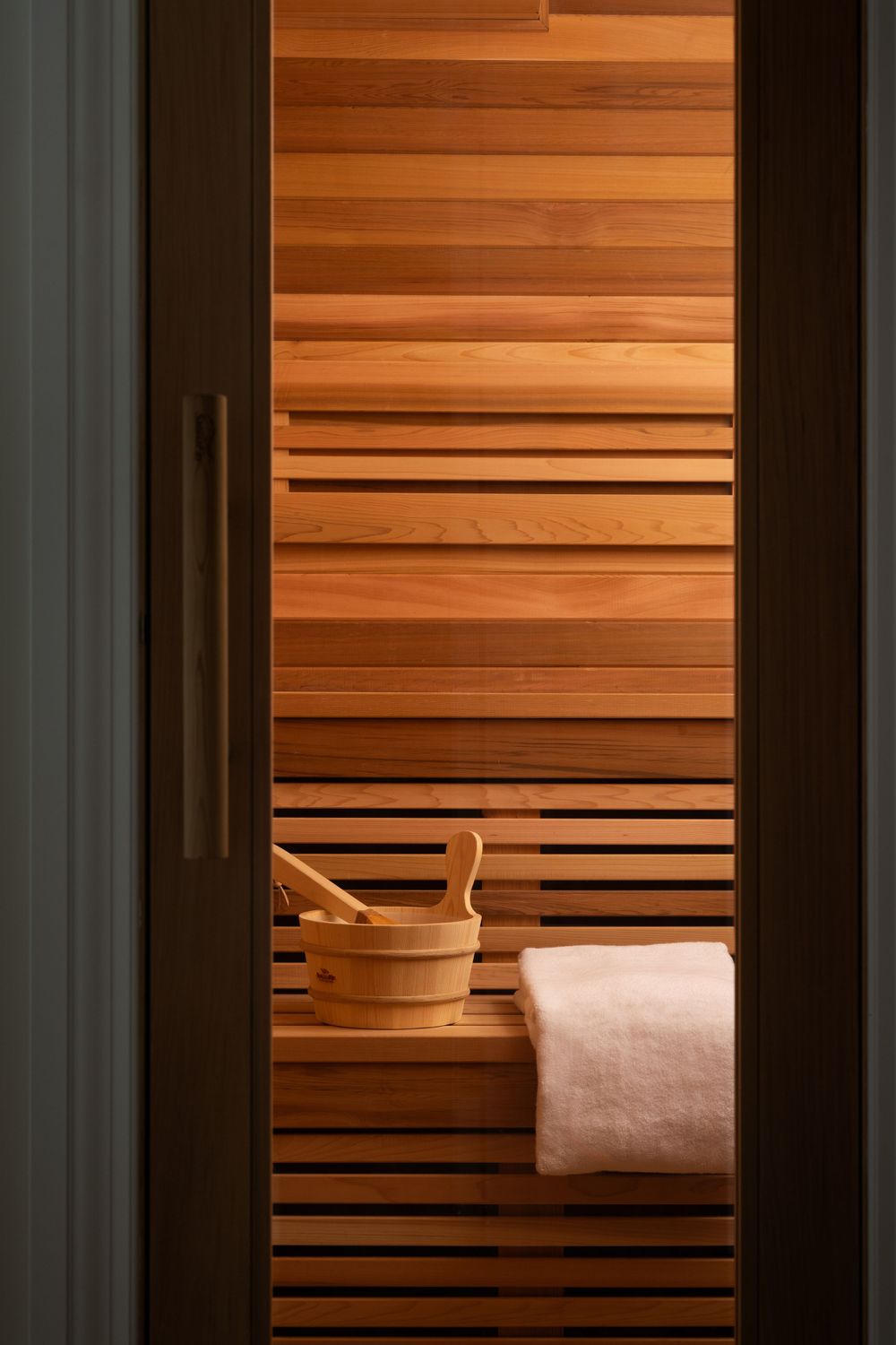 Wooden sauna interior with traditional bucket and ladle, visible through doorway.