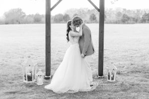 Black and white wedding portraits under wooden pergola in outdoor setting.