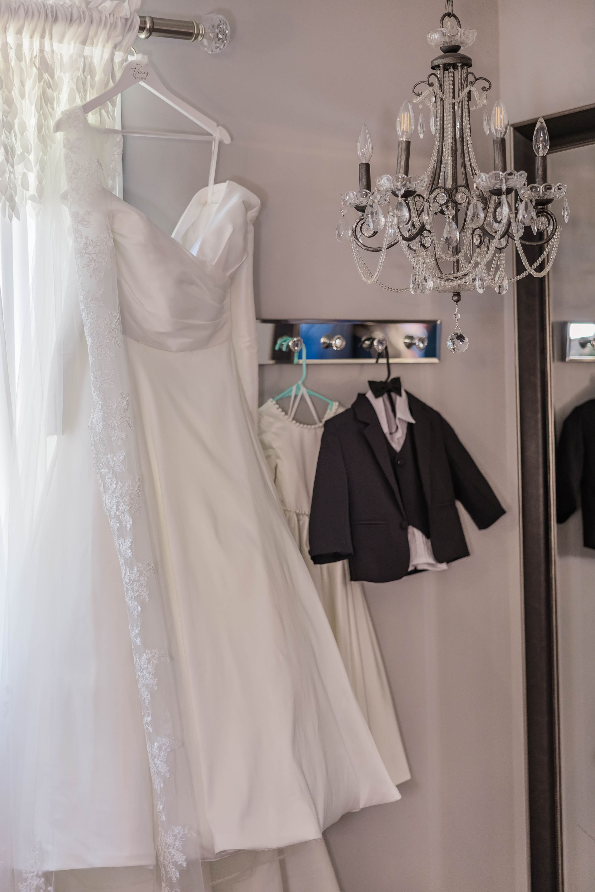 Wedding attire display shows white dresses and dark suits hanging in a bridal boutique.