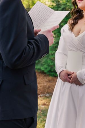 Wedding ceremony moment showing vow reading between couple in white dress and navy jacket.