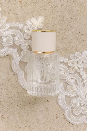 Crystal perfume bottle with gold cap placed on white lace fabric.