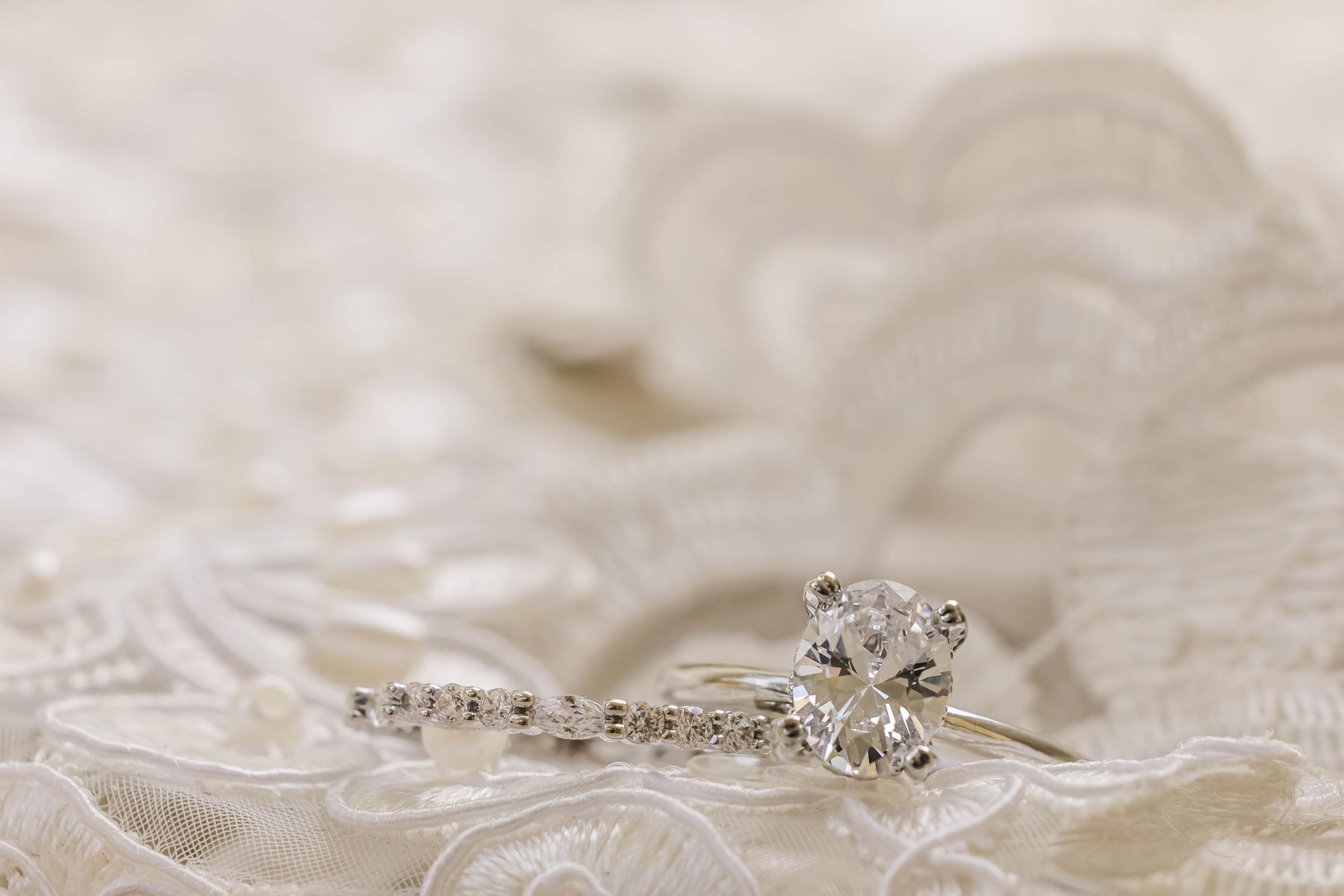 Elegant diamond engagement ring photographed on delicate white lace.
