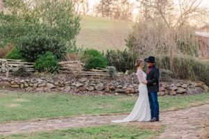 Wedding couple shares intimate moment on rustic stone path during sunset.