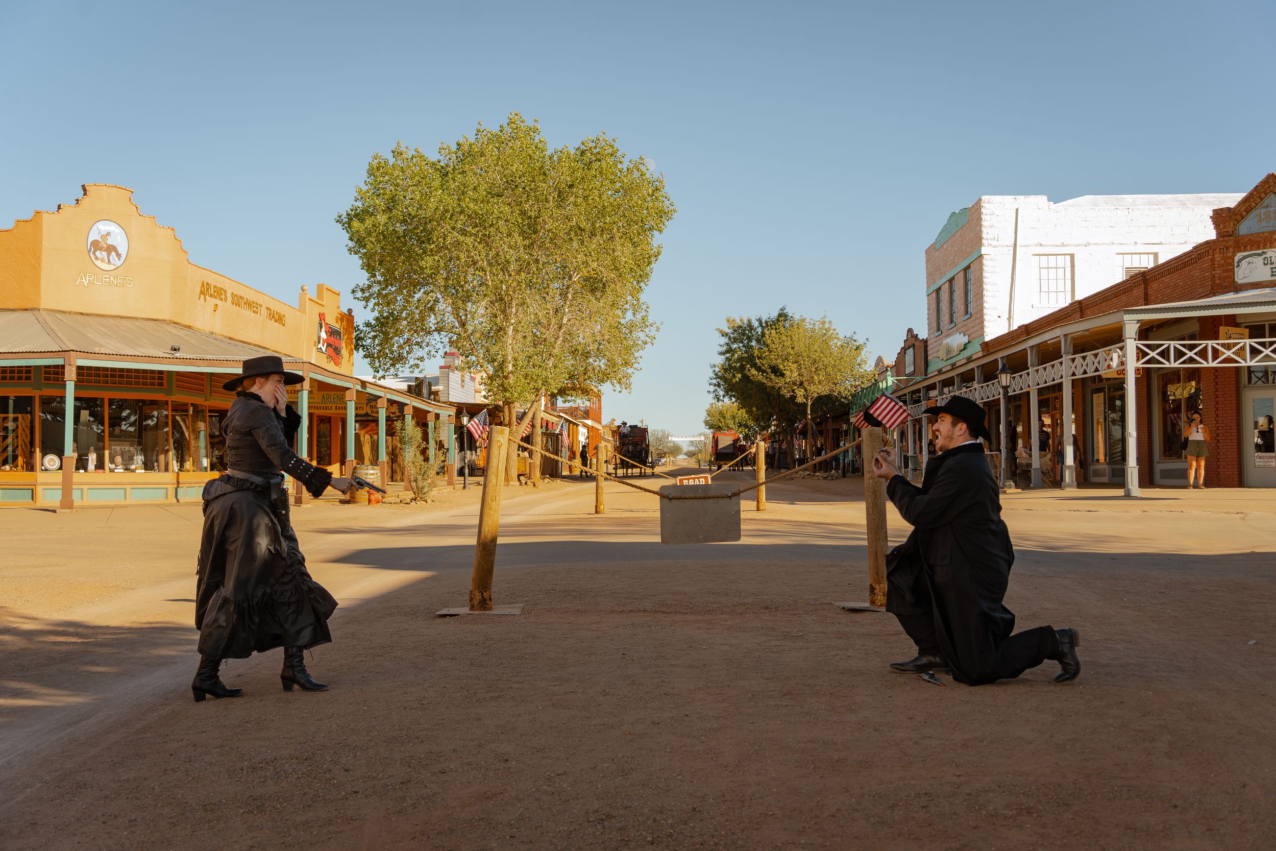 A panoramic view of an Old West town with wooden buildings and storefronts along a dusty main street.