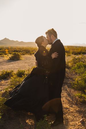 A couple embraces in silhouette against a desert landscape during golden hour sunset.