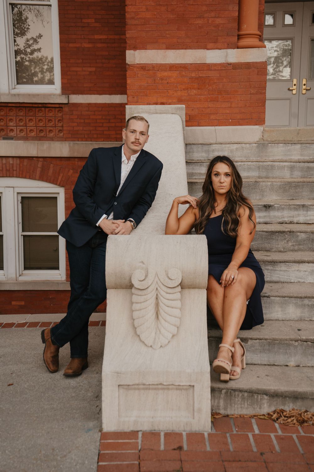 Formal couple posing on brick steps with decorative stone railing.