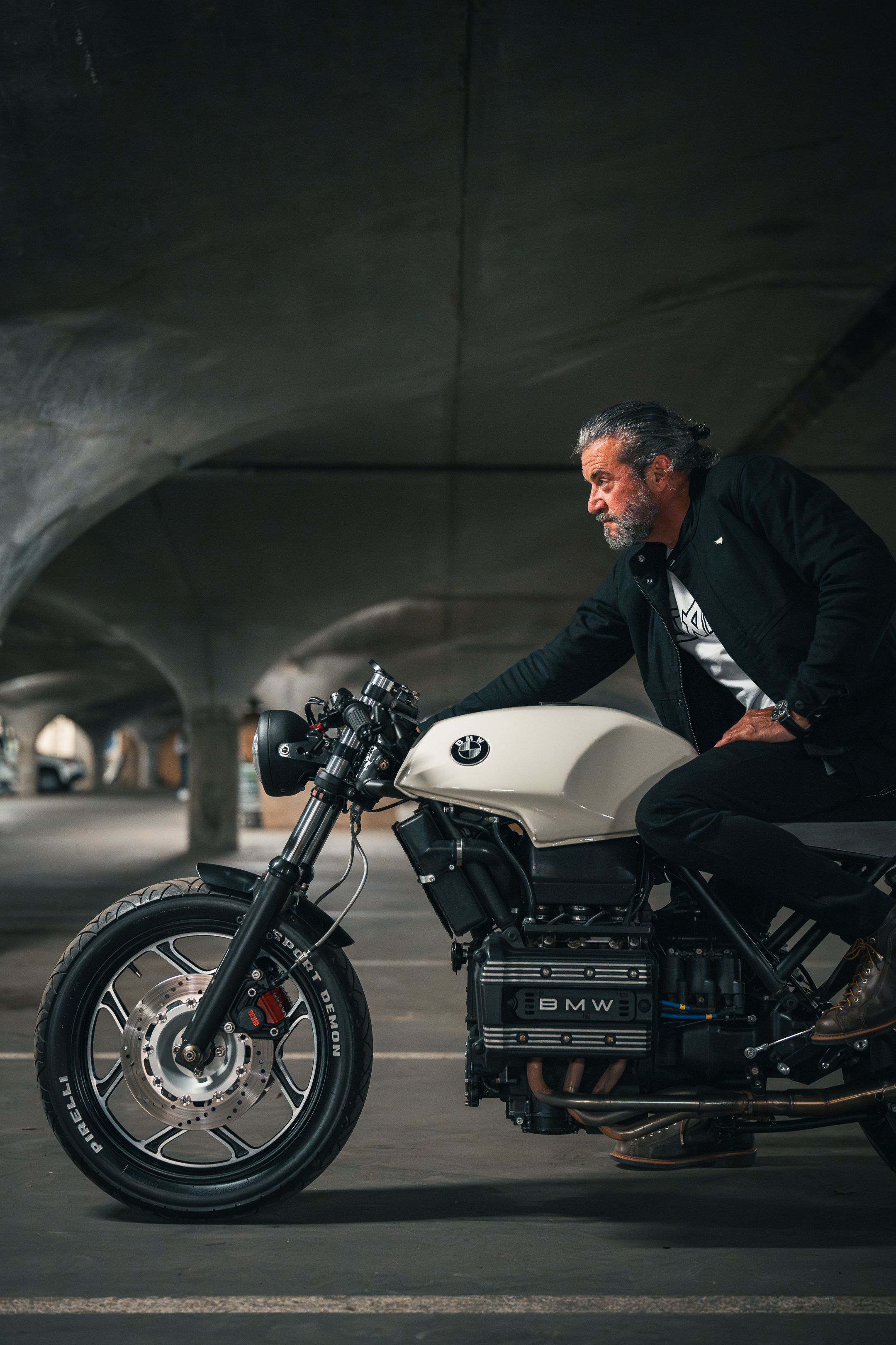 Classic BMW motorcycle with rider in urban underground setting.