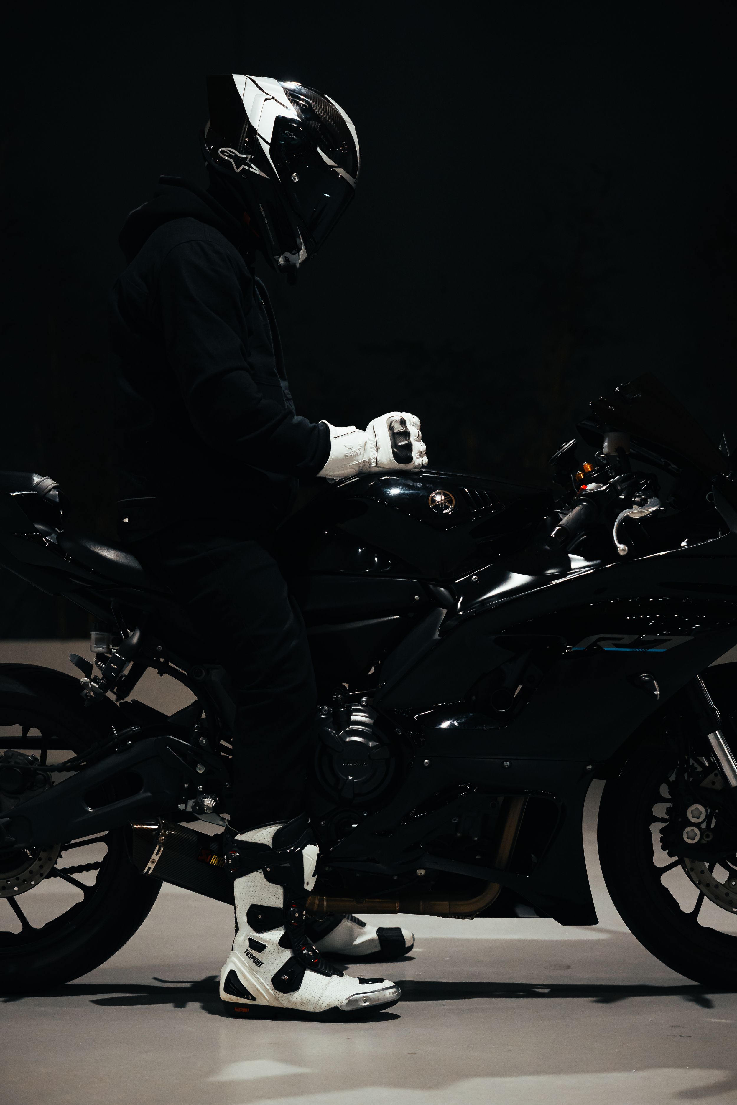 Side view of motorcycle rider in protective gear against dark background.