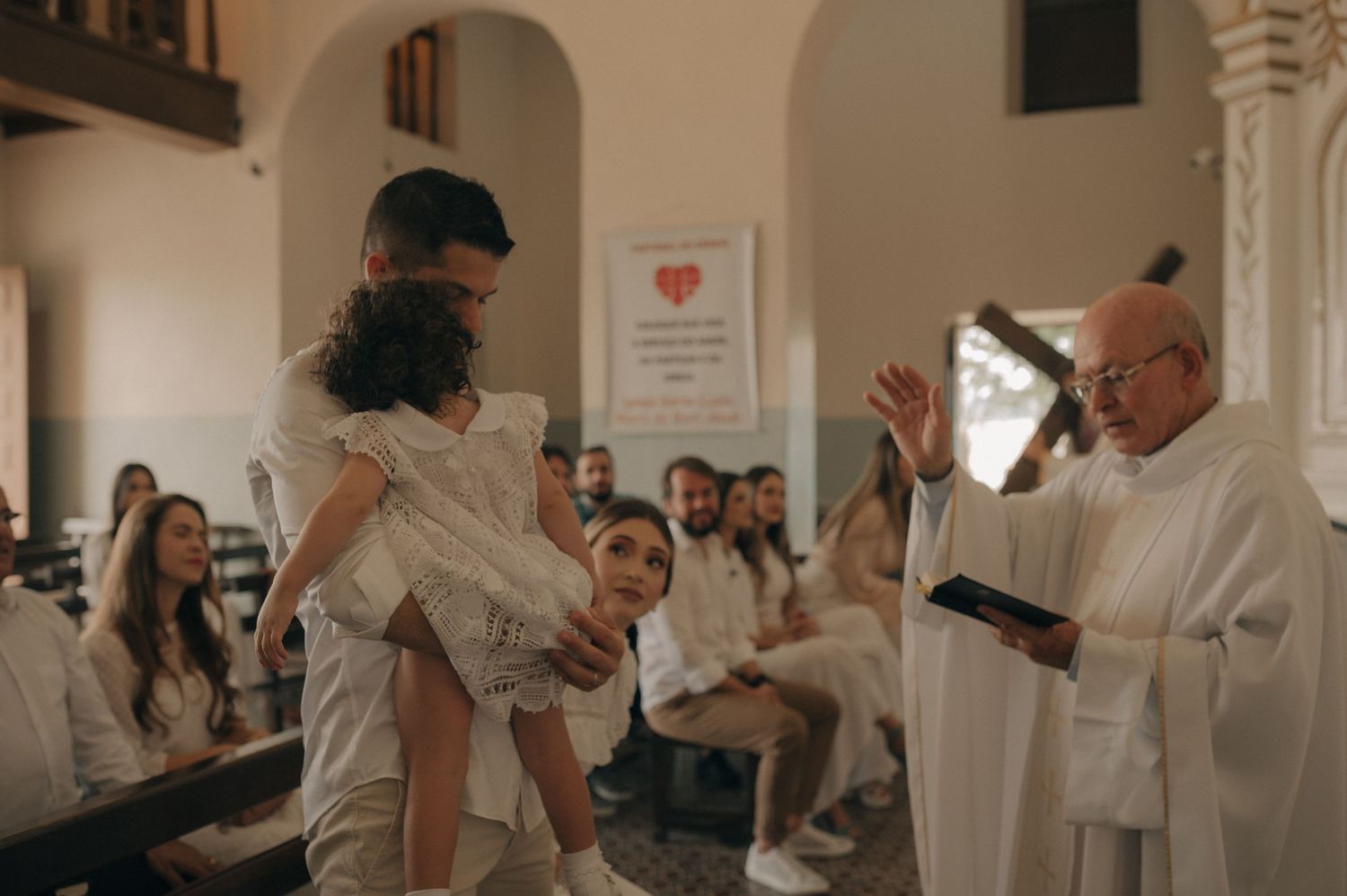 A baptism ceremony in progress with clergy and congregation in white.