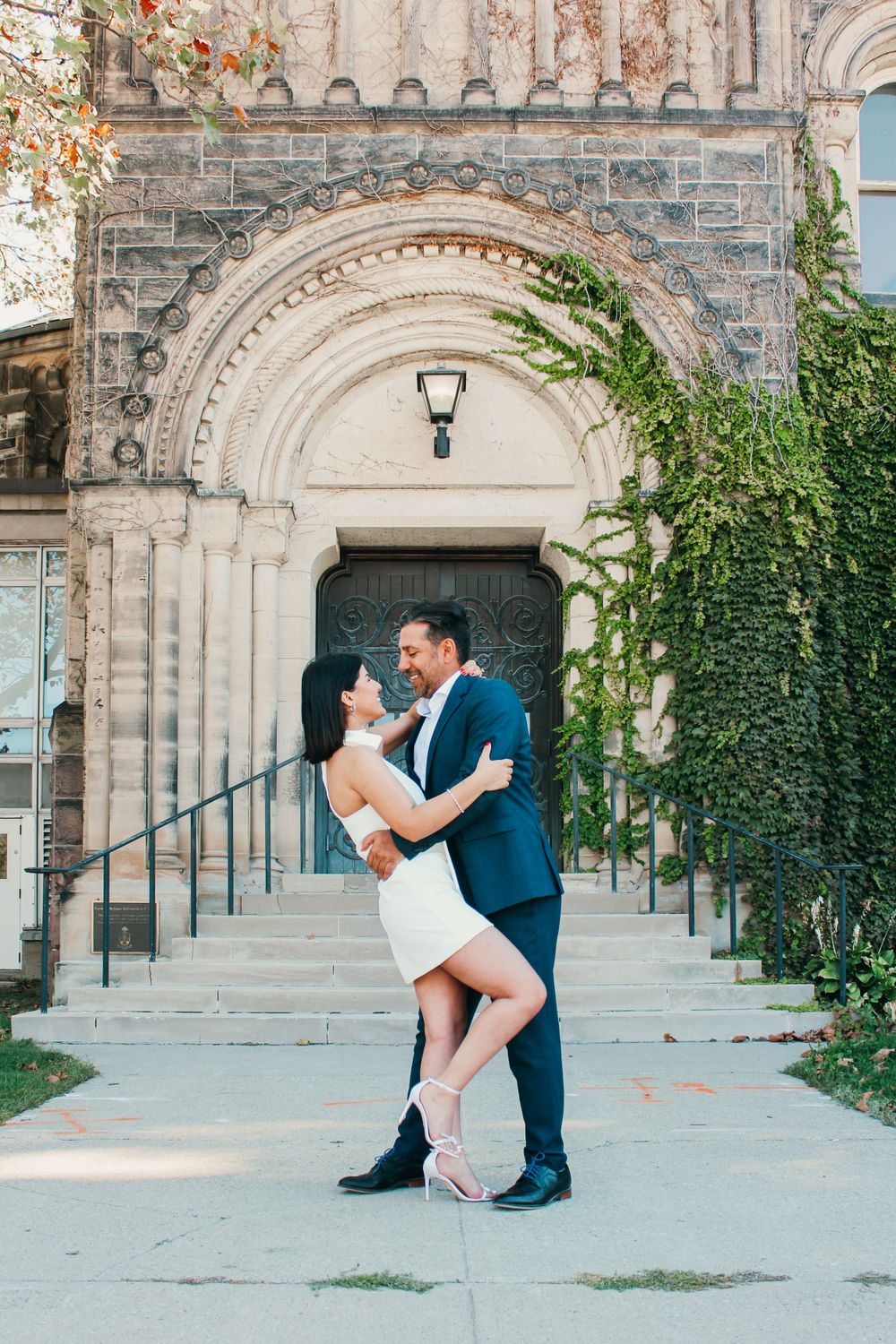 A romantic moment captured under a stone archway entrance with ivy growing along the walls.