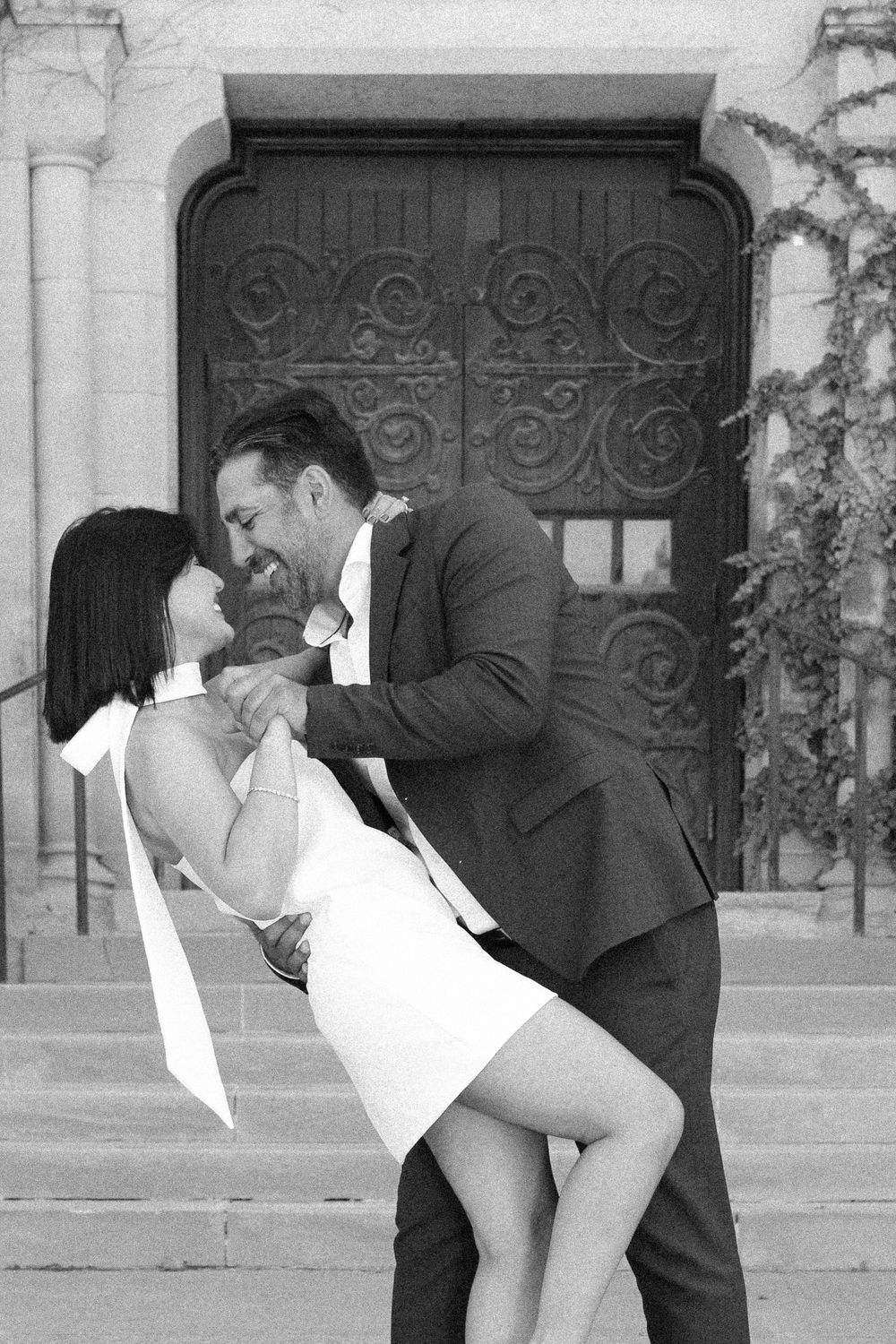A romantic black and white photo of a couple dancing in front of an ornate door.