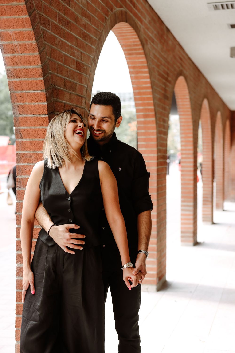 Couple sharing intimate moment under brick archway hallway.