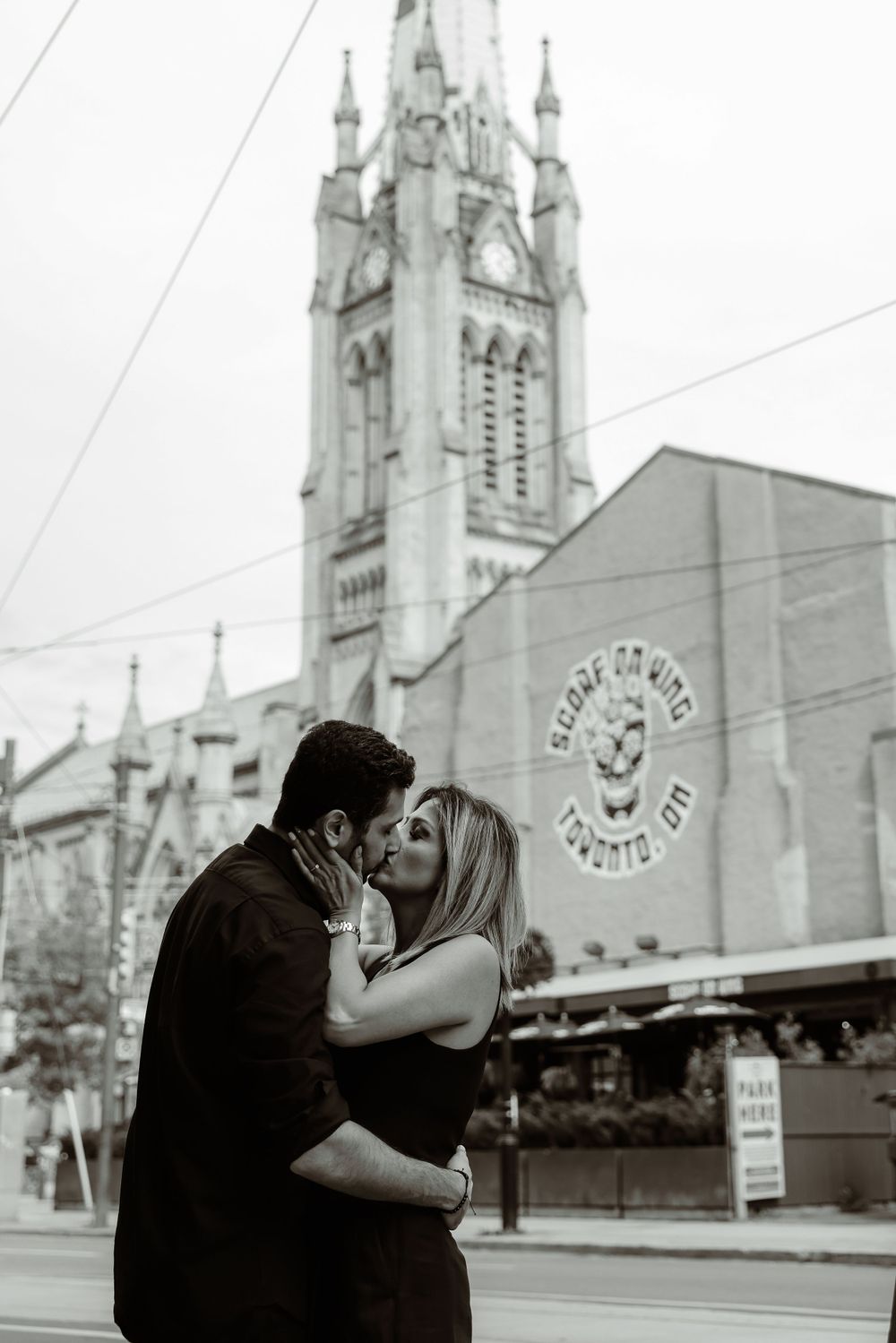Romantic moment captured in front of historic church with Gothic architecture.