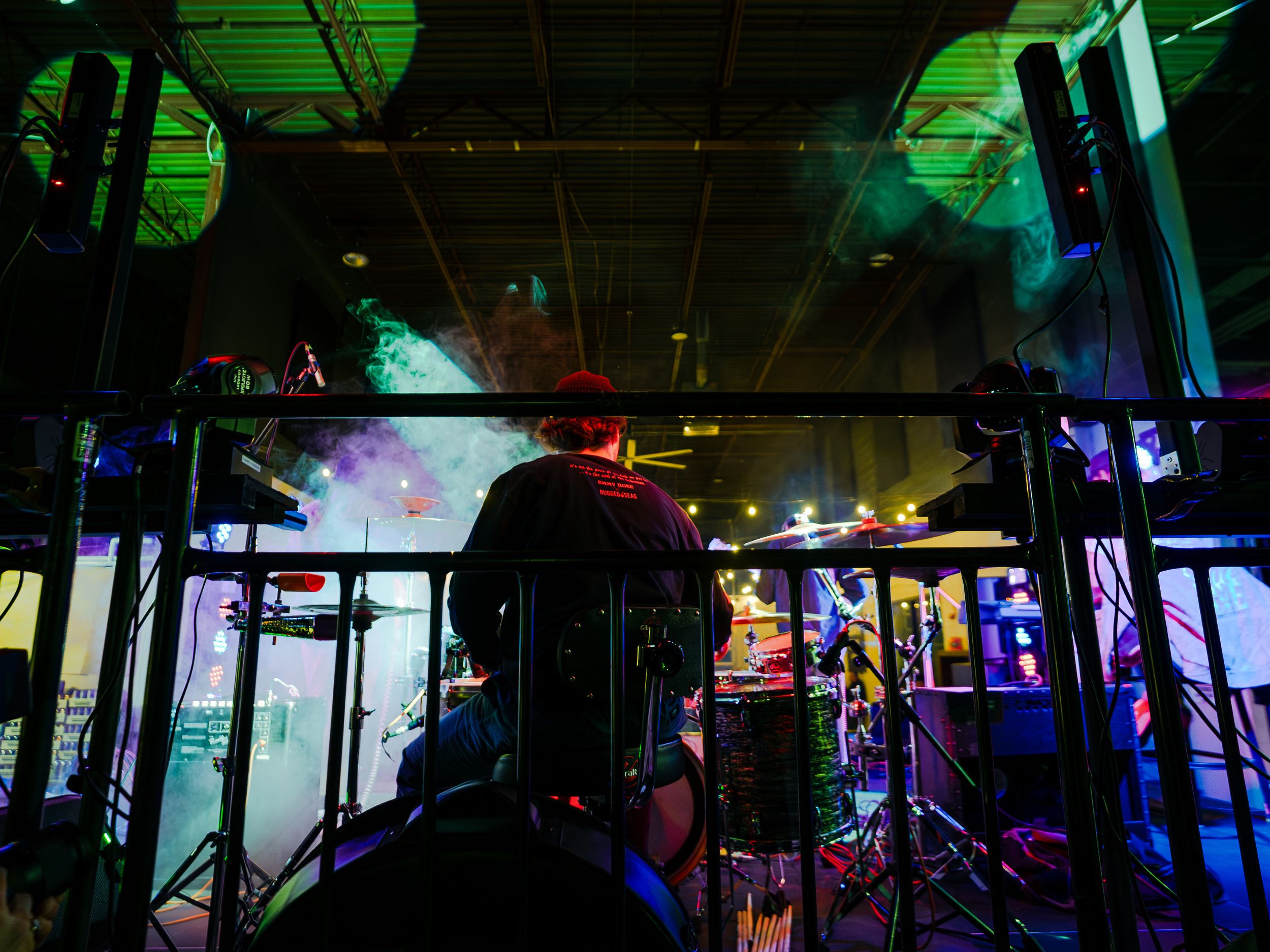 Stage lighting creates a vibrant atmosphere with blue and green hues illuminating concert equipment.