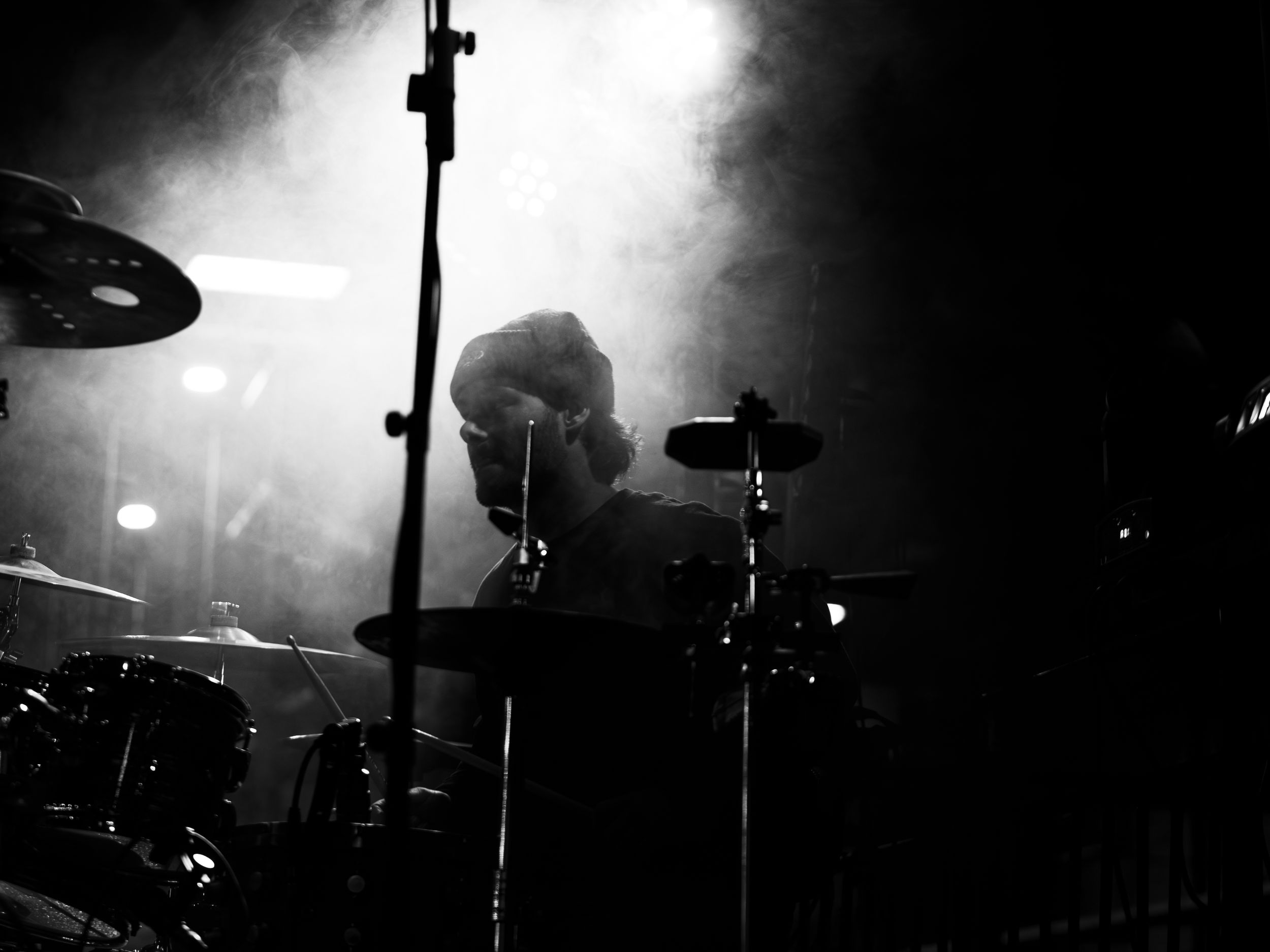 Silhouetted musical equipment and stage setup against bright white backlighting.