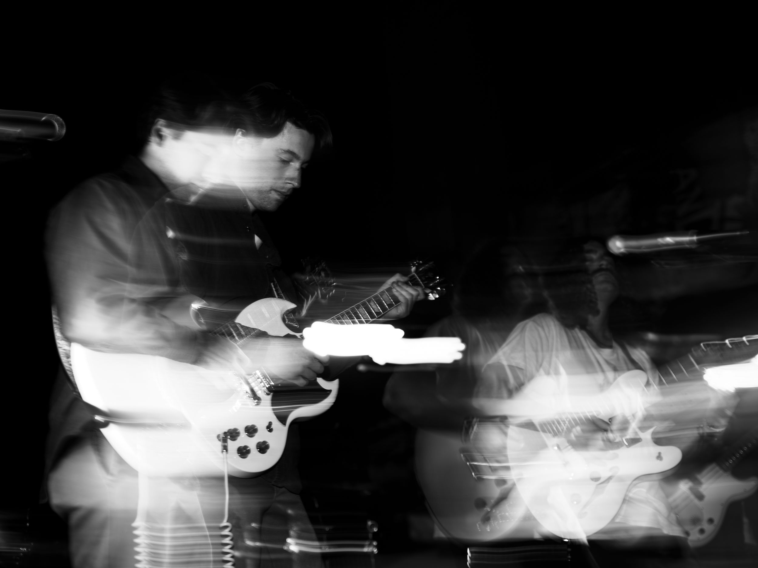 Dramatic black and white concert photography showing silhouettes of performers with stage lighting effects.