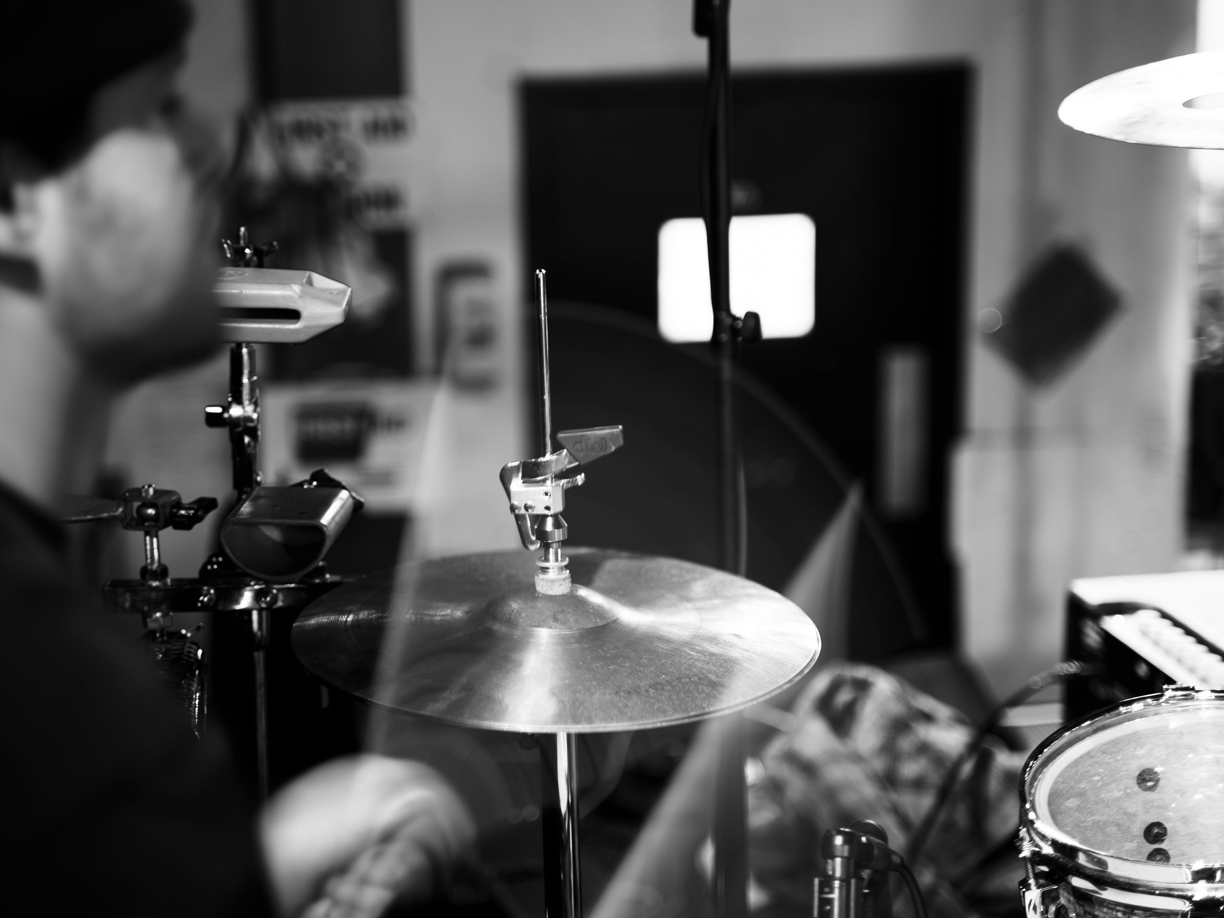Black and white image of drum cymbals and microphone stands on stage.
