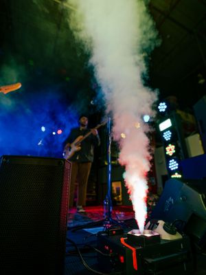 Stage performance with dramatic smoke effects and blue lighting illuminating musical equipment and instruments.