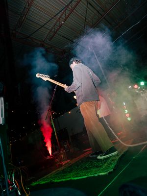 Rock concert performance with atmospheric smoke effects and dramatic lighting on an outdoor stage.