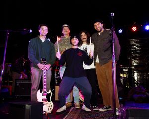 Concert venue with performers on stage under purple lighting.