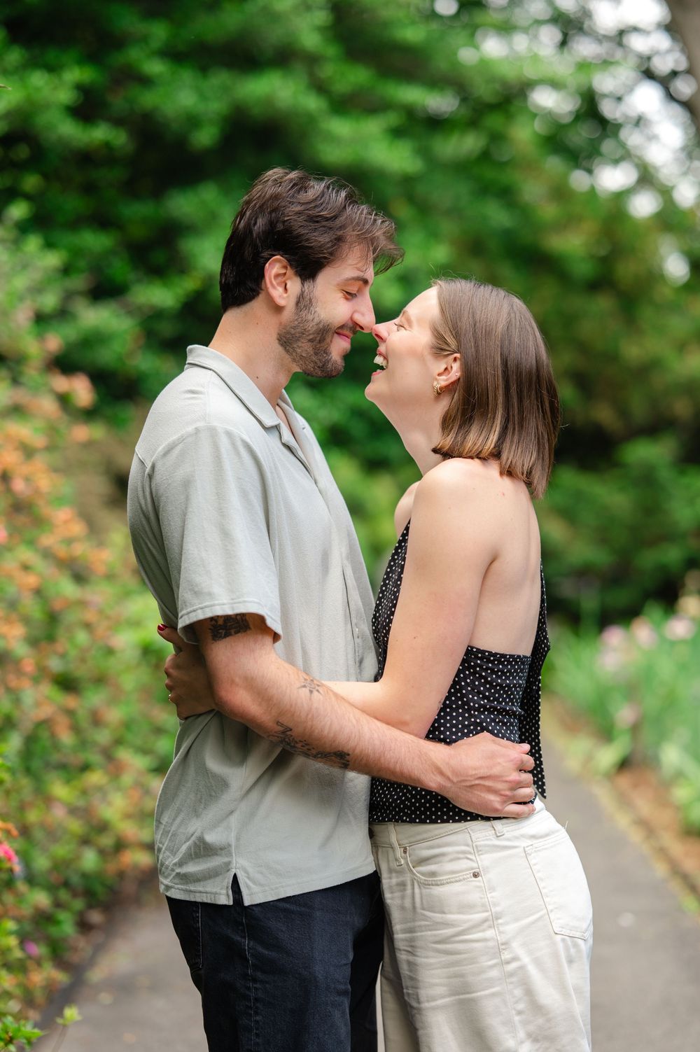 Couple sharing a tender nose-to-nose moment while embracing on a garden path surrounded by lush greenery.