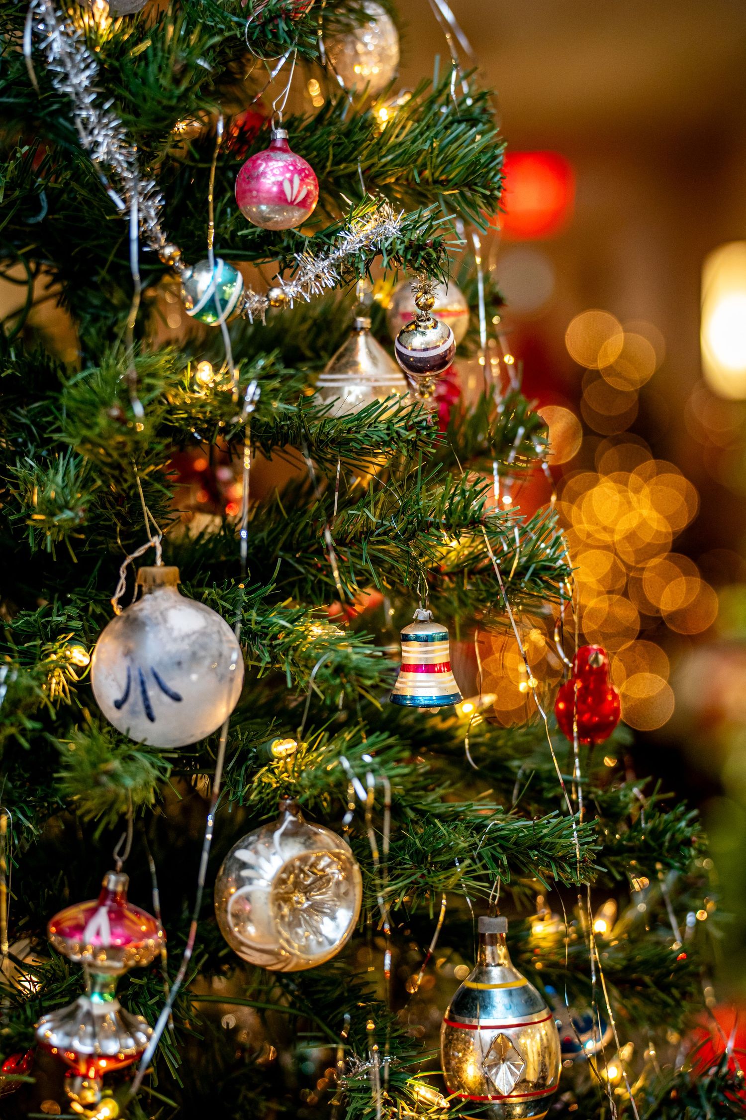 Decorated Christmas tree with vintage glass ornaments and warm bokeh lights in background.