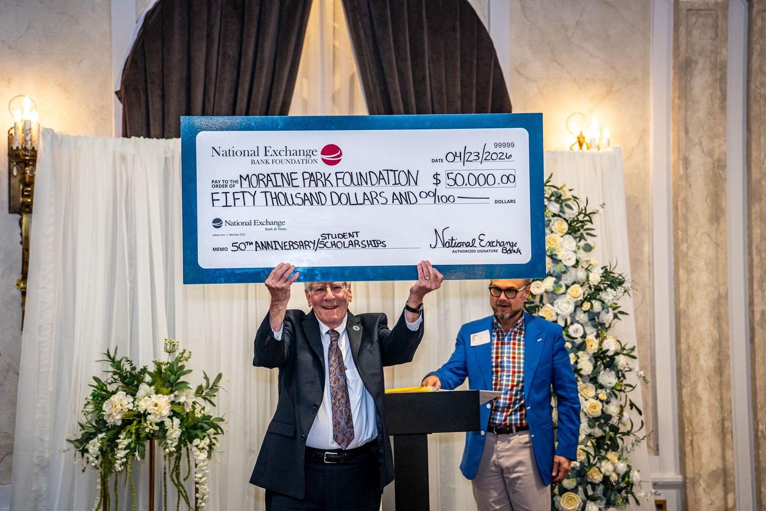 Two men proudly display a $50,000 ceremonial check for Morrone Park Foundation at anniversary celebration.