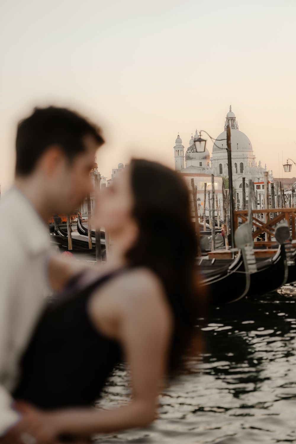 Romantic couple hugging near the gondola docks at sunrise in San Marco, Venice.