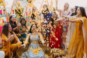 Wedding celebration with guests throwing flower petals during festive Indian ceremony.