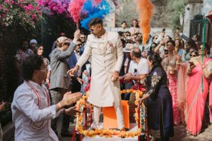 Colorful wedding celebration with guests throwing bright powder and confetti.